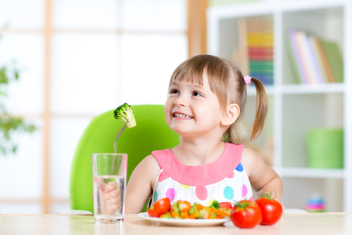 A young girl on a table eating fruits
