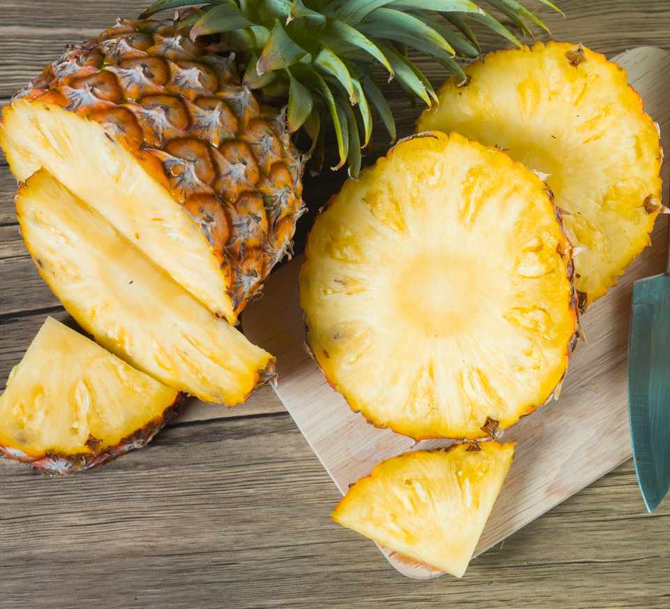A sliced pineapple on a wooden cutting board