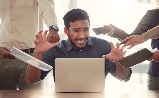 man sitting in front of a laptop with a stressed out face