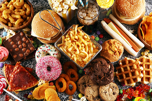 A photo of processes foods such as cookies, burgers, pizza, french fries, chips, candy and hotdog.