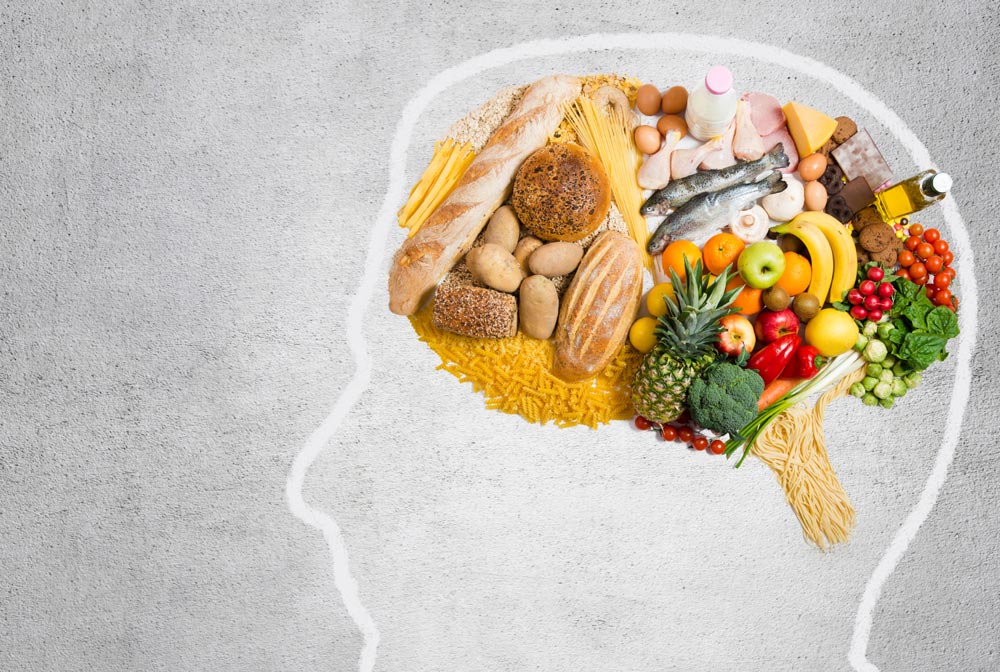 A head drawn on a table. It contains different food items drawing the brain